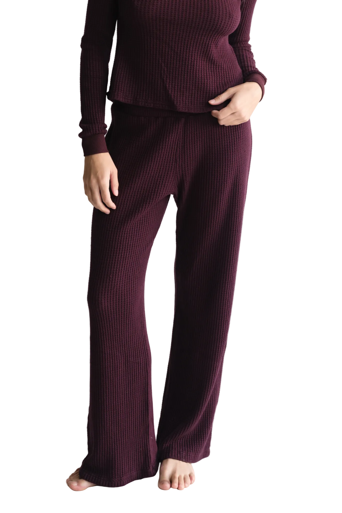 Person wearing a ribbed burgundy sweater and pants on a white background