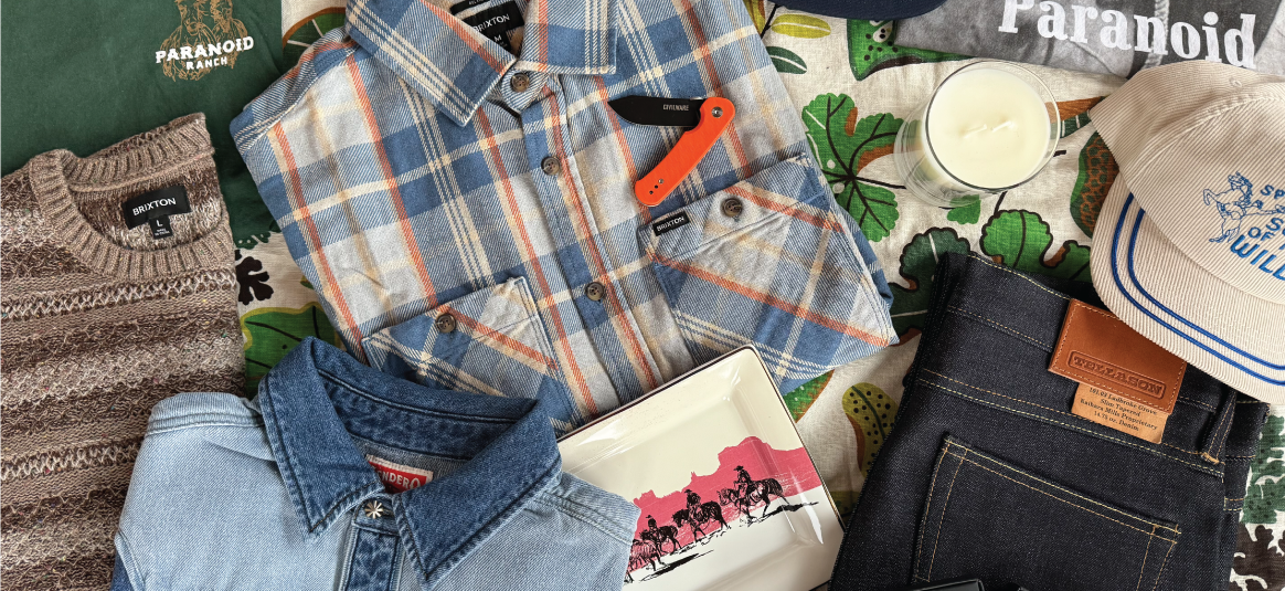 Collection of clothing and accessories including a plaid shirt, denim jacket, and hat on a green surface with 'Paranoid' branding.
