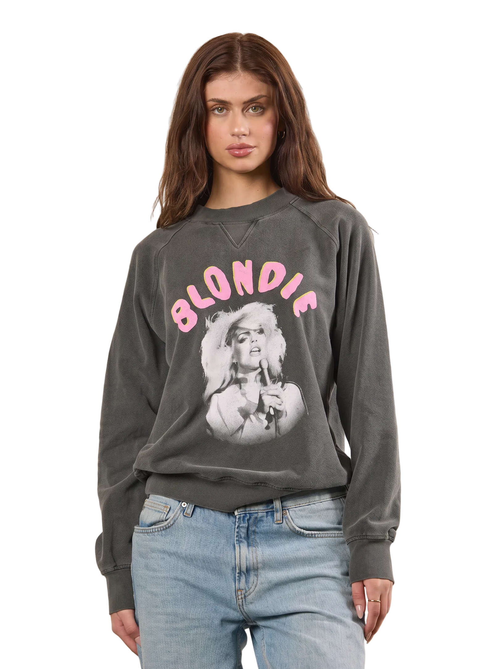 A woman modeling a dark gray crewneck sweatshirt with a pink 'BLONDIE' graphic and a black-and-white portrait print on the front, paired with light blue jeans against a solid beige background.