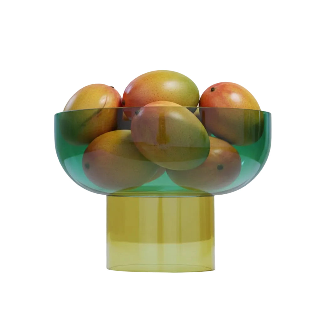 Translucent green and yellow bowl filled with mangoes on a light white background