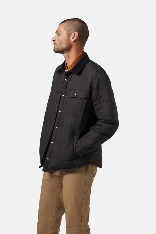 Model wearing Brixton Cass Jacket black puffer with relaxed fit and curved hem.
