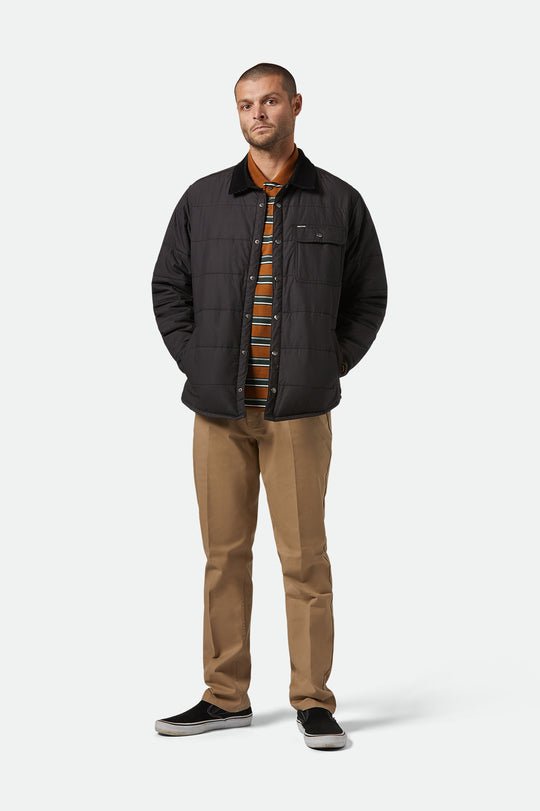 full body photo of model wearing Brixton Cass Jacket black puffer unbuttoned. 