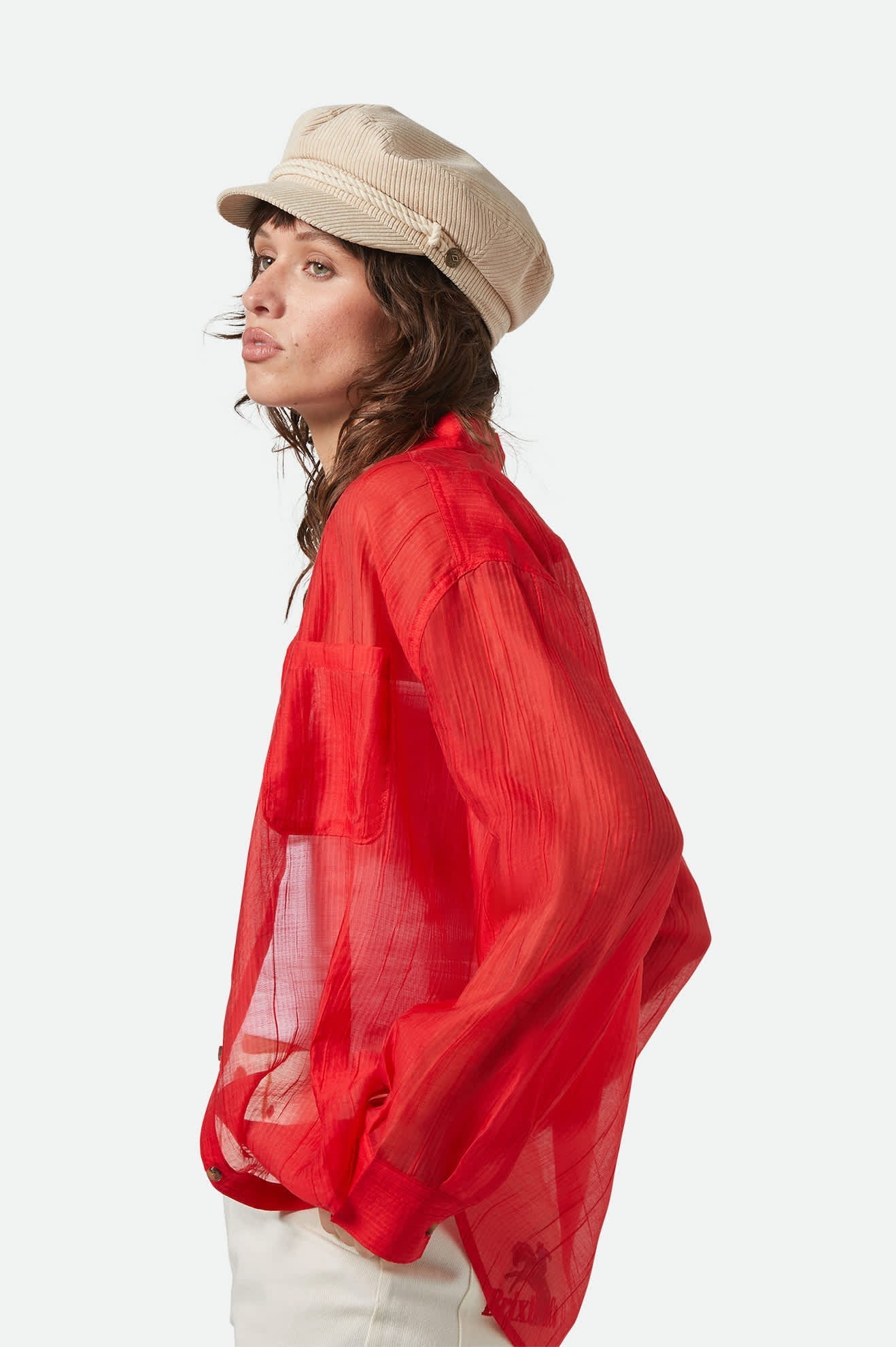 Model wearing Brixton Fiddler Cap, 1950s-inspired fisherman hat with corduroy finish and metal crest pin.