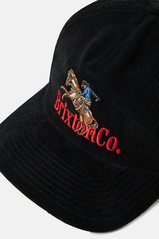 Close-up of embroidered cowboy and logo detail on black corduroy hat.