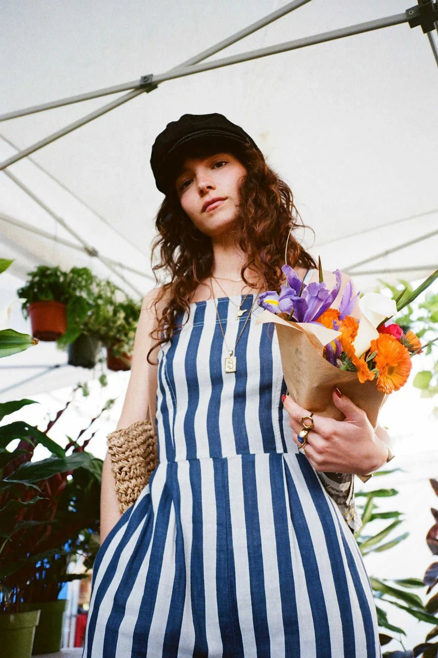 Woman wearing Mykonos Stripe Jumpsuit outdoors, summer-ready vertical stripe jumpsuit with adjustable straps and cotton fabric.