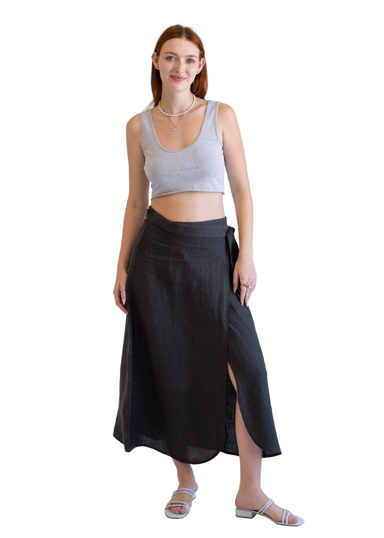 Woman wearing a gray tank top and black wrap skirt on a white background