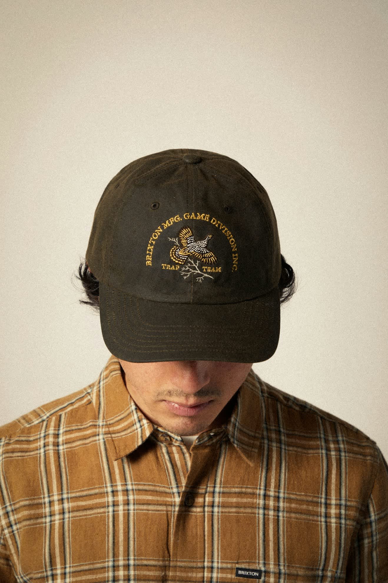 Model wearing Brixton Game Weather Cloth Netplus Adjustable Hat with waxed cotton finish and recycled visor.