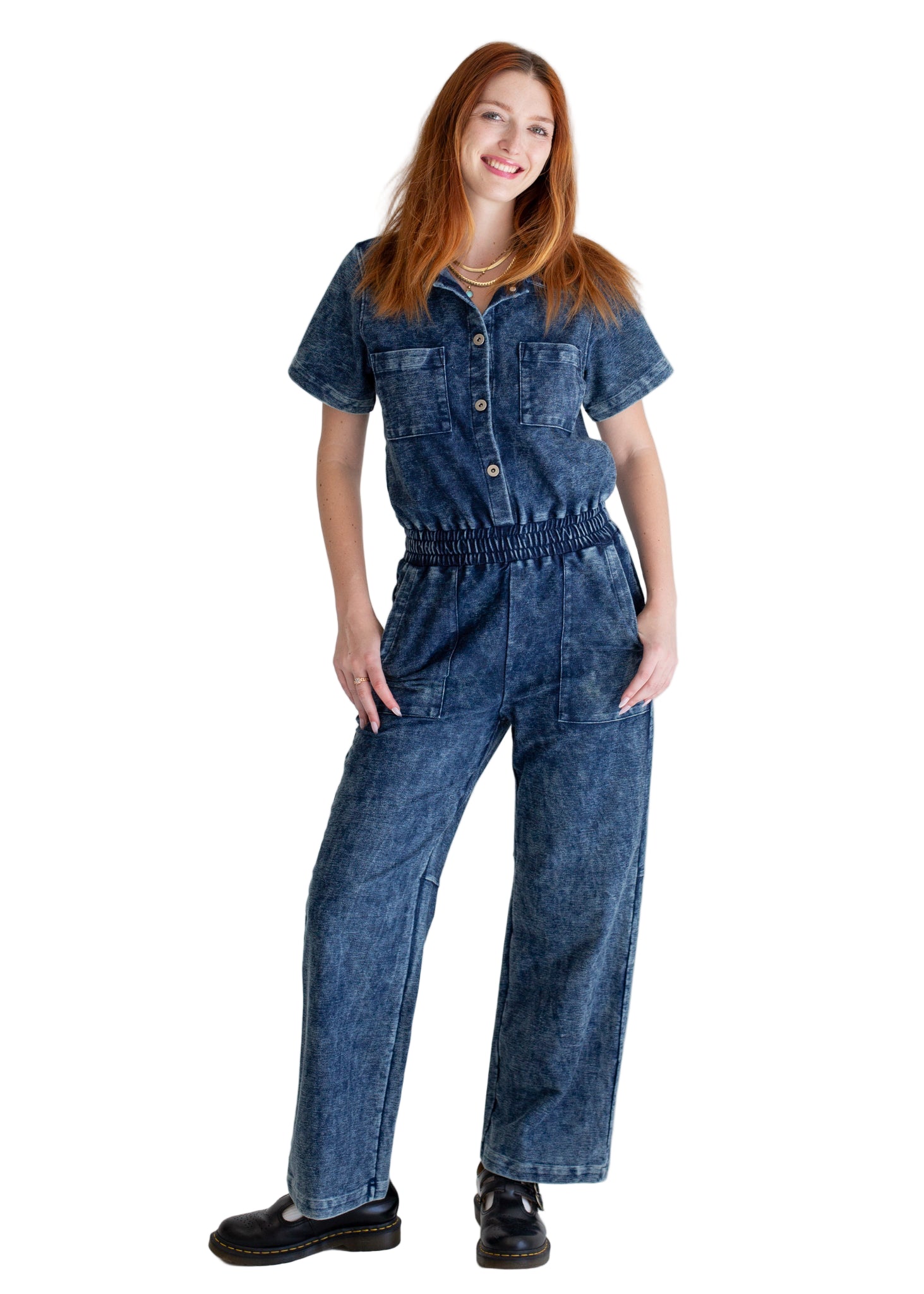 Woman wearing a blue denim jumpsuit on a plain background