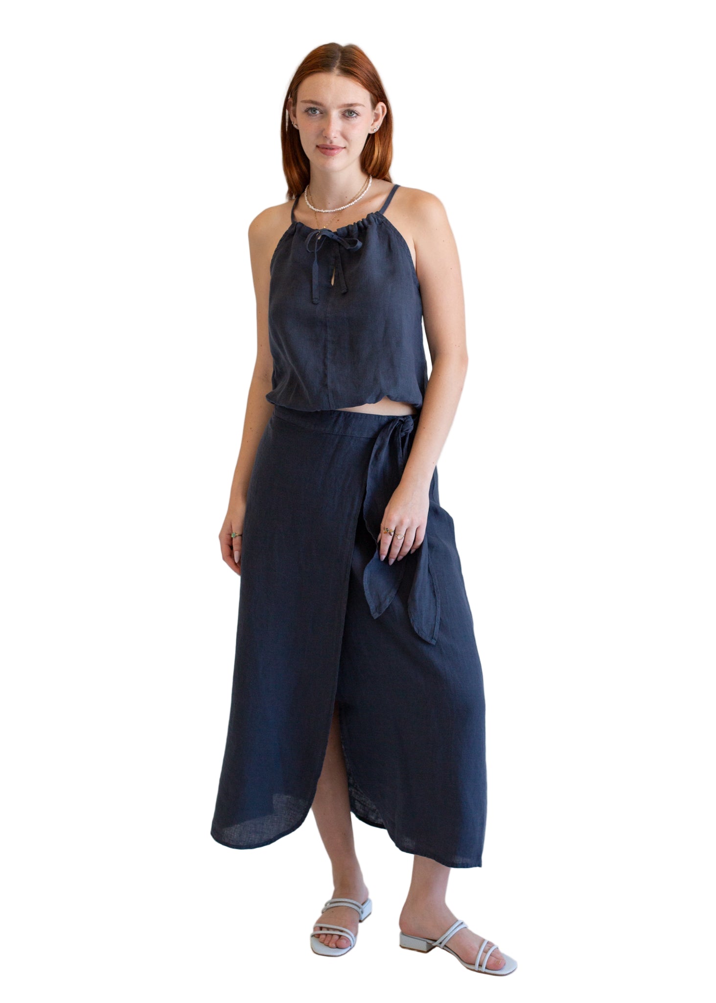 Woman wearing a navy blue sleeveless top and long skirt on a white background