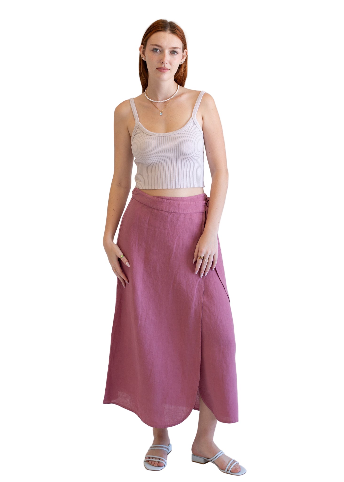 Woman wearing a white tank top and pink skirt on a white background