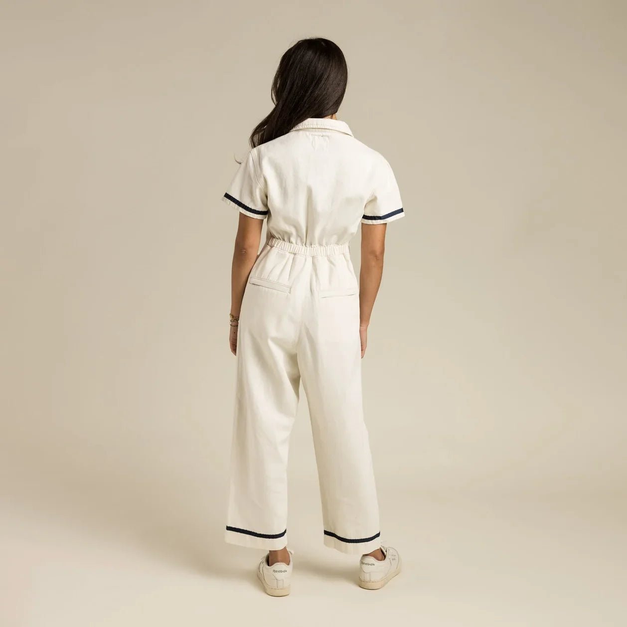 Comfortable ecru jumpsuit with elastic back waist, center front zip, and subtle navy detailing for retro Western style.