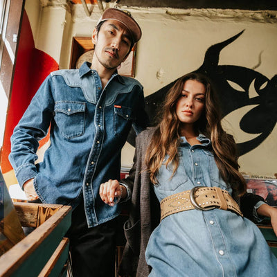 male and female models wearing Sendero Pearl Snap Denim Shirt in medium wash with western piping, pearl snaps, and classic cowboy style.